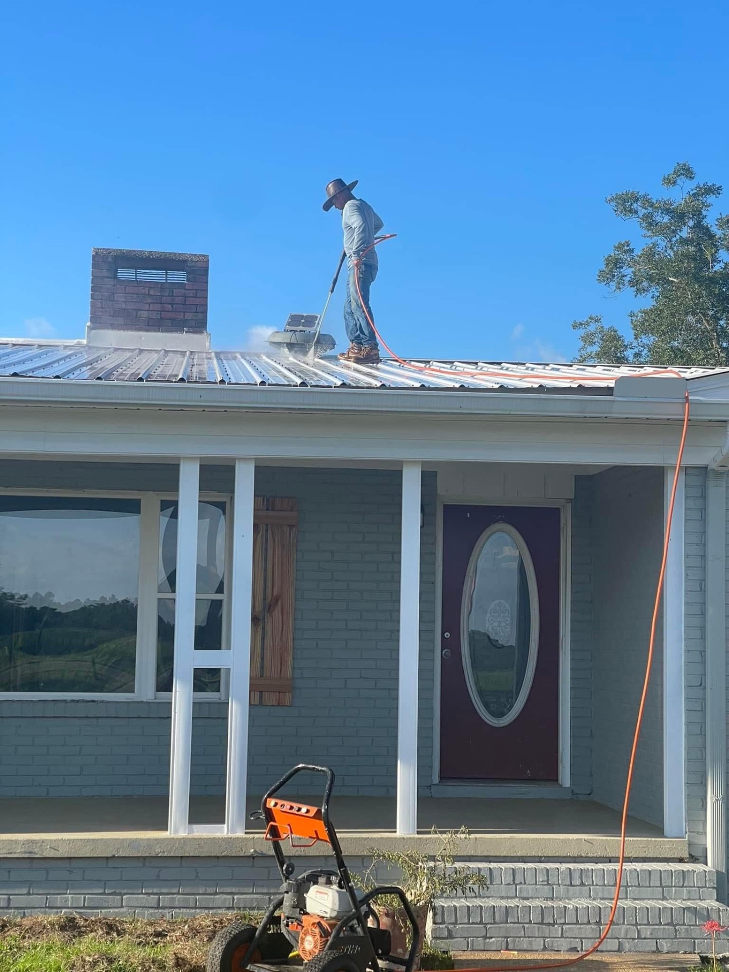 Worker pressure washing a metal roof
